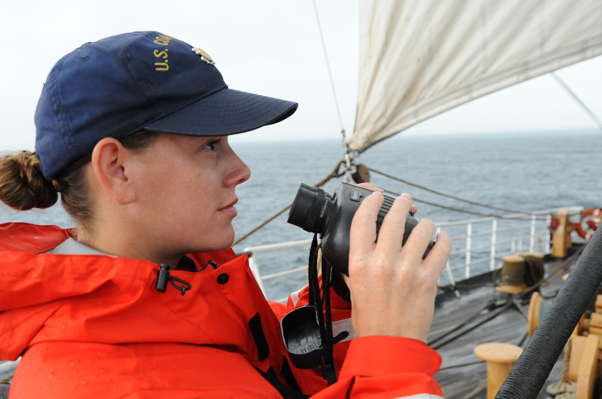 Coast Guard member stares off into the distance aboard a cutter
